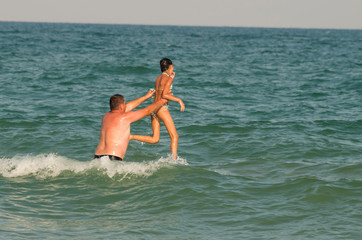 Father casts his daughter high in the waters of the sea. Family jumping game in the ocean.  Summer, family vacation and relax on the beach of ocean.