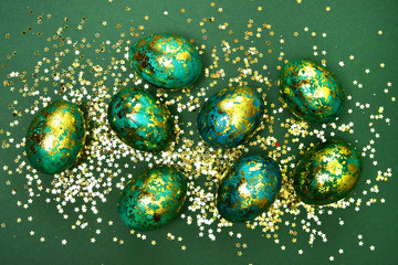 Easter eggs, dark green with gold on a green background. View from above. Flat lay.