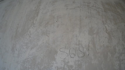 Background gray concrete wall with the inscription hand SOS black, wall shabby