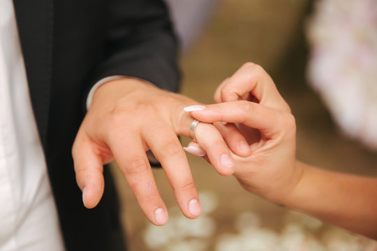 Close up of hands groom and bride wearing a ring