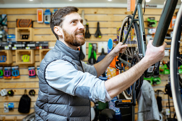 Happy man with passionate emotions standing near a new bicycle at the bicycle shop