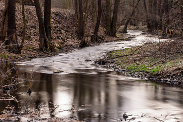 Fototapeta na wymiar River with blurry water in forest.