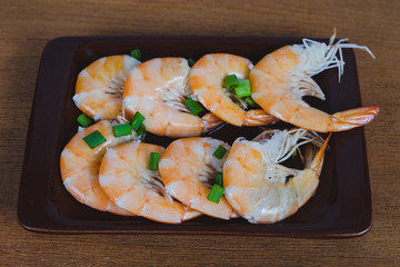 Steamed white shrimp in dish on wood background.