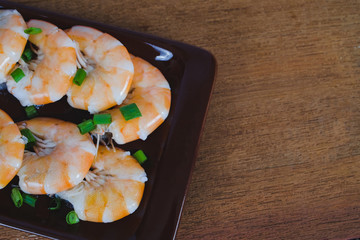 Steamed white shrimp in dish on wood background.
