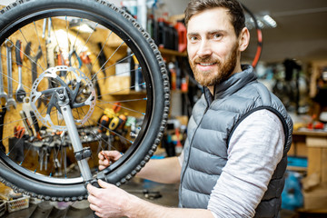 Fototapeta na wymiar Man aligning bicycle wheel tensing spokes with a special key at the working place of the workshop