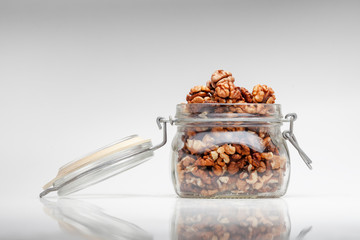 Glass jar with shelled walnuts on table on a white background