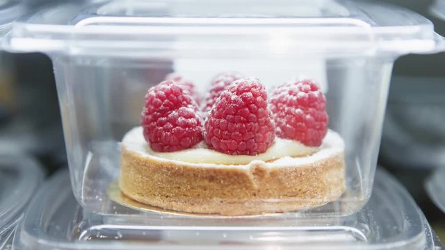 Small raspberry cake for dessert eating.Delicious little cake in refrigitator packed in plastic container.Fresh sweet pastry for coffee break.
