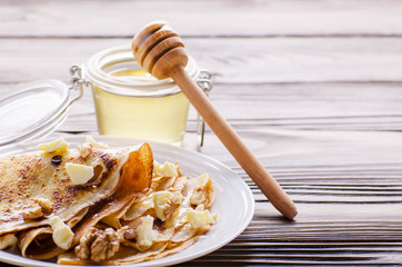 French crepes with butter and honey in ceramic dish on wooden kitchen table