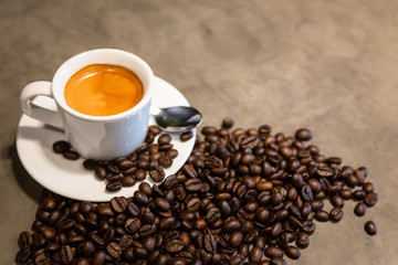 Espresso in a cup of hot coffee and coffee beans on concrete polishing floors (cement) background in loft style in a cafe shop,fresh espresso with crema (perfect shot) in morning,top view, copy space
