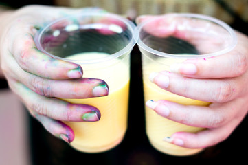 Colorful hands holding disposable cups of thandai on hindu festival holi