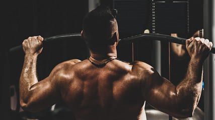 Athletic young man doing heavy weight exercise for back, with color imitating social network filter