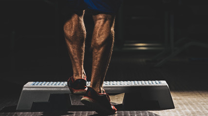 Back view of strong healthy athlete training calves in gym, with color imitating social network filter © Denys Kurbatov