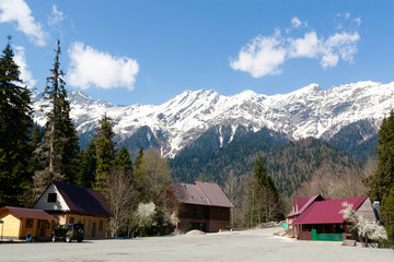 Snow on the mountains. Spring landscape on the background of houses