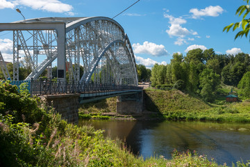 First in Russia steel arch bridge on river Msta in sunny summer day. Novgorod region, Borovichi, Russia. Was built in 1905.