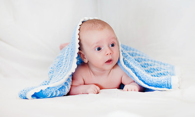 Portrait of a cute smiling infant baby crawling in a diaper, two-month baby child holds head