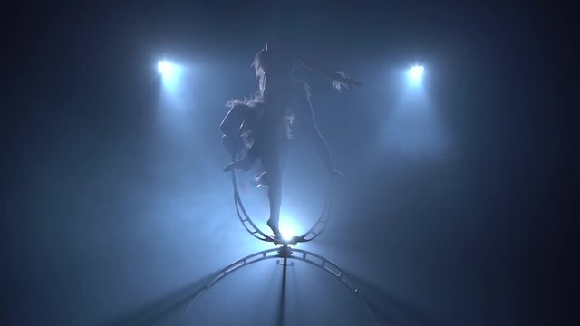 Representation of two acrobats in the air on stage. Black smoke background. Silhouette