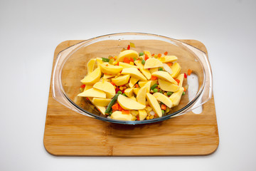 potatoes with vegetables baked in the oven in a glass container with a lid. cutting Board and white background