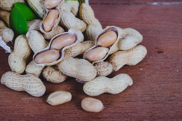 Peanut spill out of basket on wood background