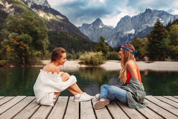 Two young tourist women have fun on the dock on lake