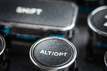 An extreme close-up or macro shot of a round ALT and OPT key on a vintage-inspired retro-style clicky black-and-silver metal typewriter keyboard.