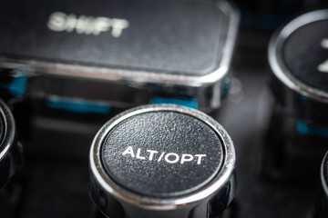 An extreme close-up or macro shot of a round ALT and OPT key on a vintage-inspired retro-style clicky black-and-silver metal typewriter keyboard.