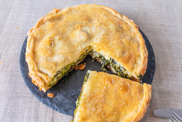 Sliced pie with broccoli and cheese on a black slate dish, top view - vegetarian cuisine.