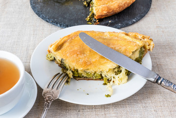 A piece of delicious vegan homemade pie with broccoli and cheese on a white plate closeup - vegetarian, healthy cuisine.