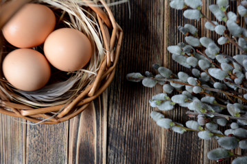 Eggs in basket and willow on wooden table Easter concept