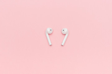 White wireless Bluetooth headphones on pastel pink background