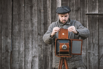 Photographer prepares for shooting and inserts film holder into retro large format camera. Concept...