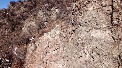 Climbers climb the rock. Drone footage. Side and top view. Rock lesson in the highlands. Gray rocks...