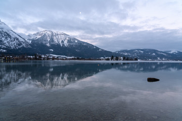 Wolfgangsee mit Spiegelung der schneebedeckten Berge im Hintergrund im klaren Wasser, treibendes...
