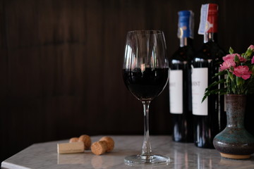 Glass of red wine and bottle of wine on wooden table