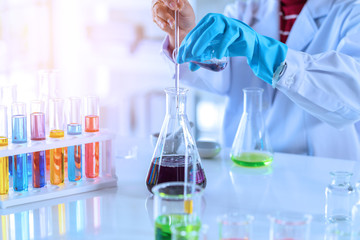 scientist with equipment and science experiments, laboratory glassware containing chemical liquid for research or analyzing a sample into test tube in laboratory