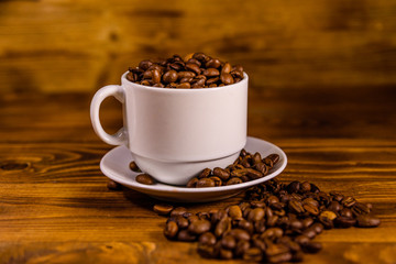 White cup filled with coffee beans on wooden table
