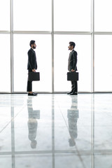 Fototapeta premium Two businessmen deep in discussion together while standing in an office boardroom with windows