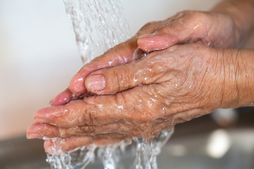 Fototapeta premium Senior woman washing her hands, Flowing and Splashing water, Close up & Macro shot, Selective focus, Healthcare concept