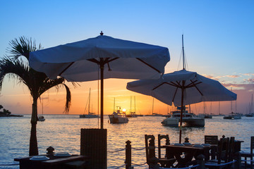 Beautiful sunset on the sea beach cafe or restaurant, boats, ships and yachts on water background