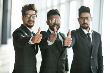 Portrait of indian businessmen standing together and giving thumbs up in office