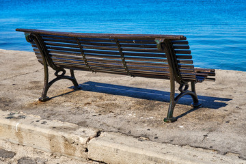 Single old-fashioned cast iron and wood park bench on a sunny day