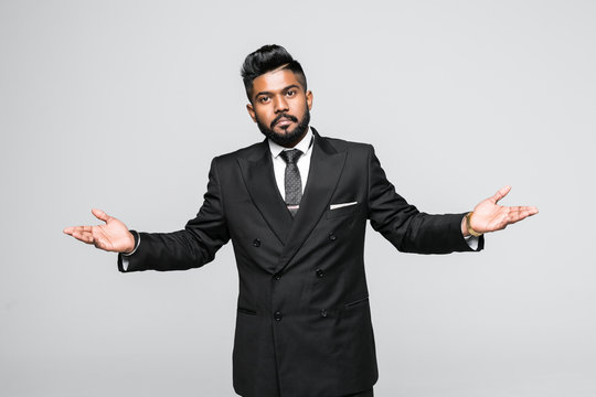 Portrait, dumb clueless young indian man, arms out asking why what's the problem who cares so what, I don't know. Isolated white background.