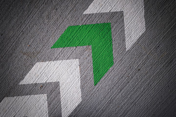 Betonwand mit weißen und grünem Pfeilen