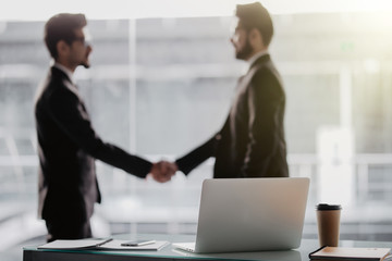 Two business people shaking hands in office as sign of partnership in office