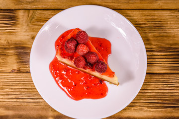 White plate with cheesecake New York and raspberries on wooden table. Top view