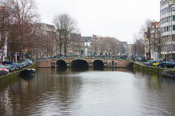 Early spring scene in Amsterdam city. Tours by boat on the famous Dutch canals. Cityscape with canal houses in Holland, Netherlands