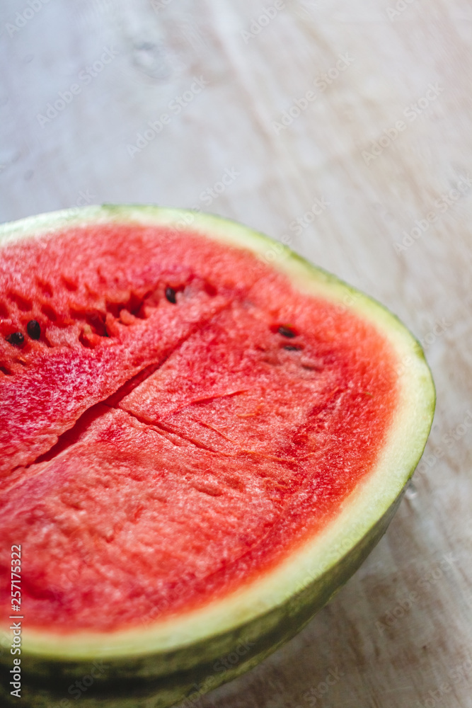 Sticker Half a juicy watermelon on a light white wooden background, close-up. View from above