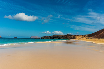 Fototapeta na wymiar Untouched white sand beach with crystal clear waters on a beautiful summer day. Exotic landscape of Playa de las Conchas one of the most popular beaches on La Graciosa Island, Canary, Spain.