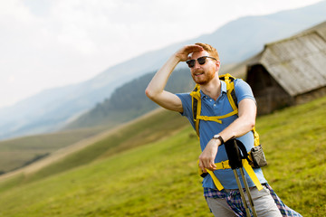 Fototapeta na wymiar Handsome young red hair man with sunglasses hiking on the mountain