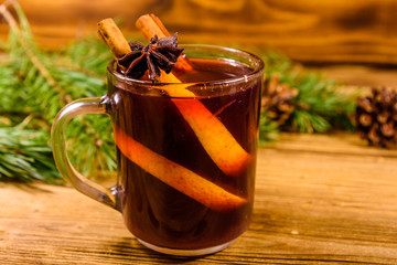 Cup of mulled wine with cinnamon and fir tree branches on wooden table