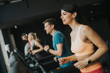 young people running on treadmills in modern gym